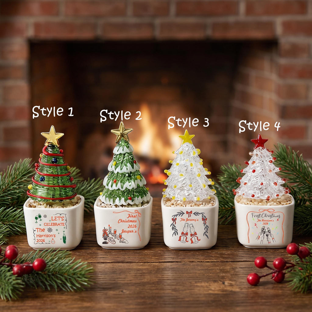 May include: Four miniature Christmas tree ornaments in square white ceramic pots. Style 1 is green with a gold star. Style 2 is green with white snow and a gold star. Style 3 is clear with yellow lights and a yellow star. Style 4 is clear with red lights and a red star.