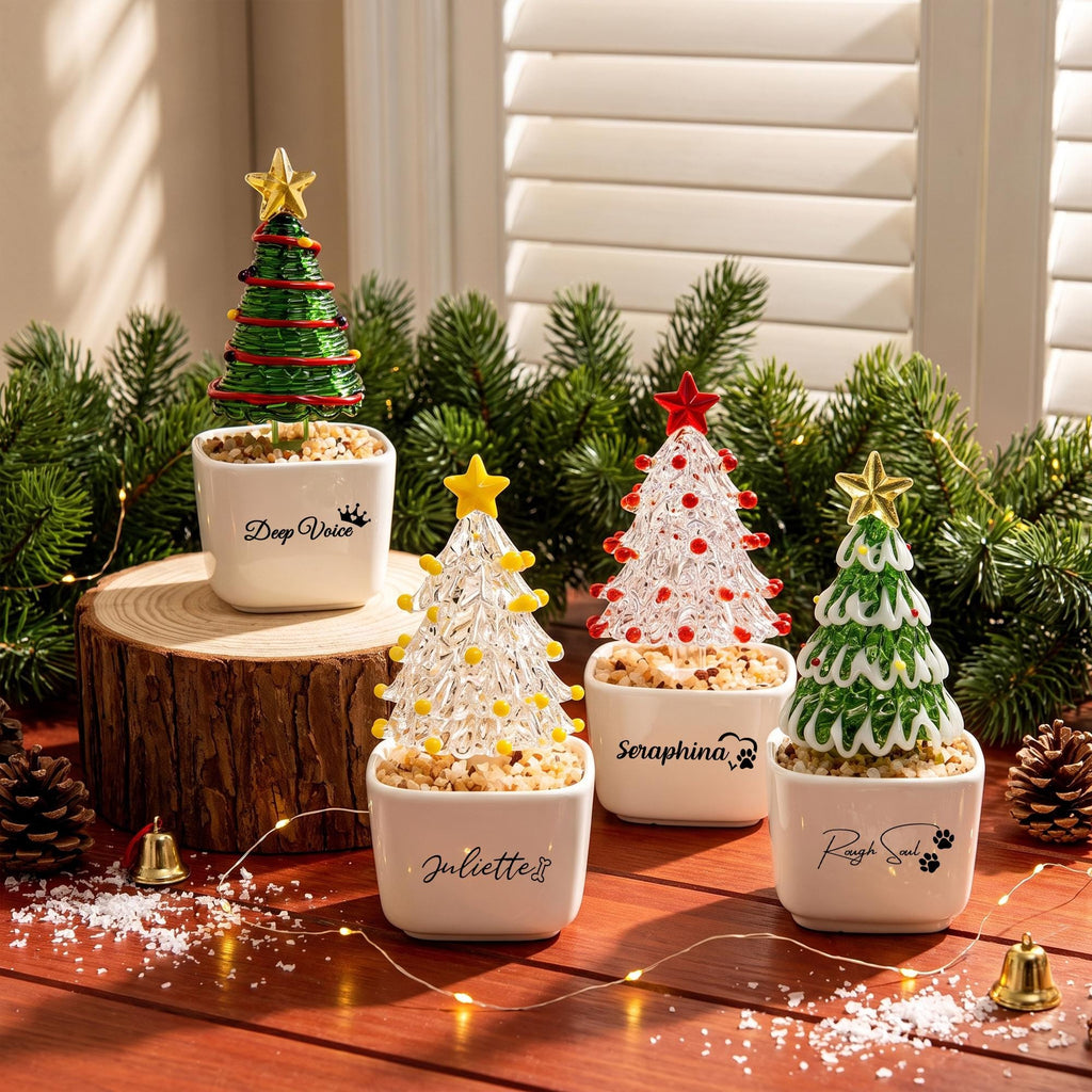 May include: Four miniature Christmas tree ornaments in white square pots filled with pebbles. The trees feature green, clear, and white glass designs topped with gold or red stars. Pots are labeled with names: Deep Voice, Juliette, Seraphina, and Rough Soul.