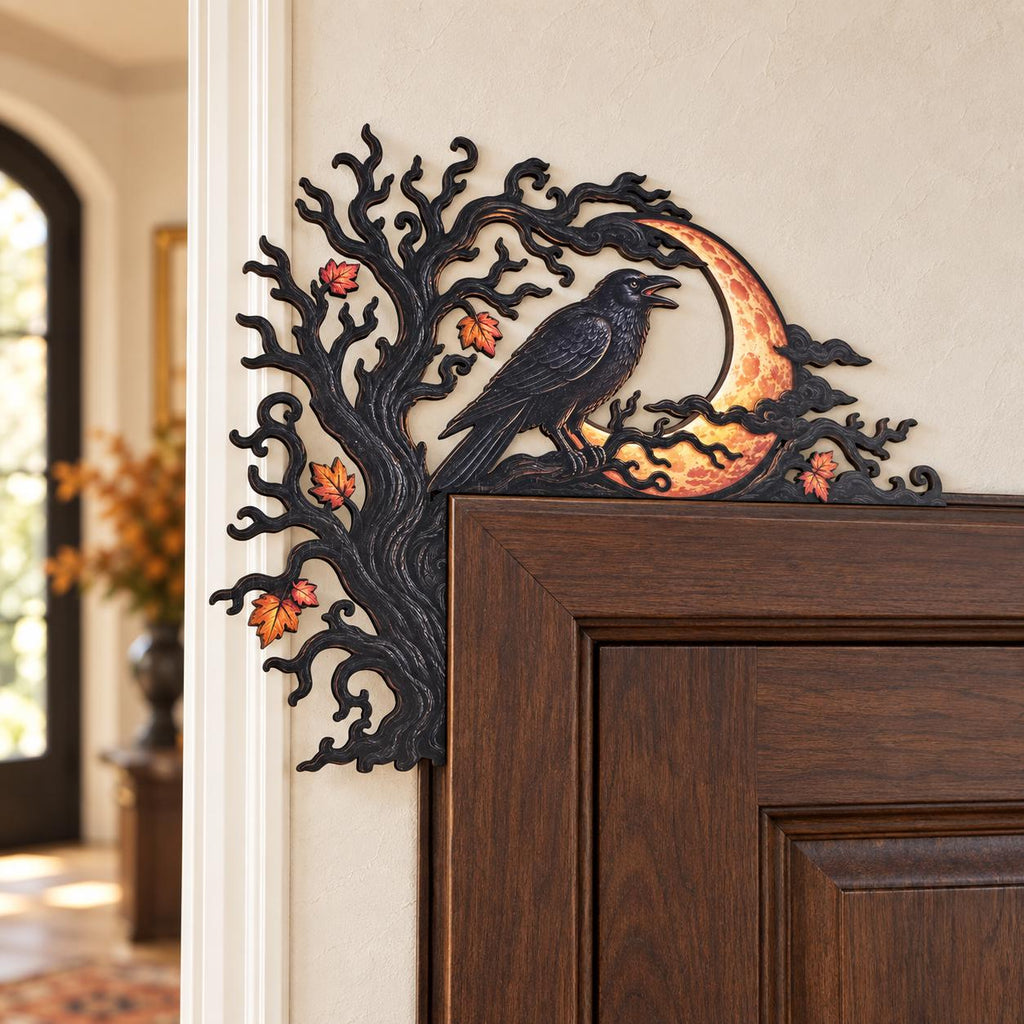 May include: A black decorative door corner accent featuring a gnarled tree silhouette with orange and red autumn leaves. A black raven is perched on a branch in front of a textured, glowing orange crescent moon, all set against a dark frame.