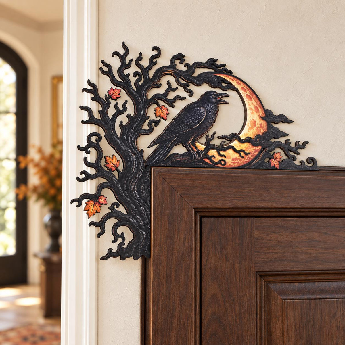 May include: A black decorative door corner accent featuring a gnarled tree silhouette with orange and red autumn leaves. A black raven is perched on a branch in front of a textured, glowing orange crescent moon, all set against a dark frame.