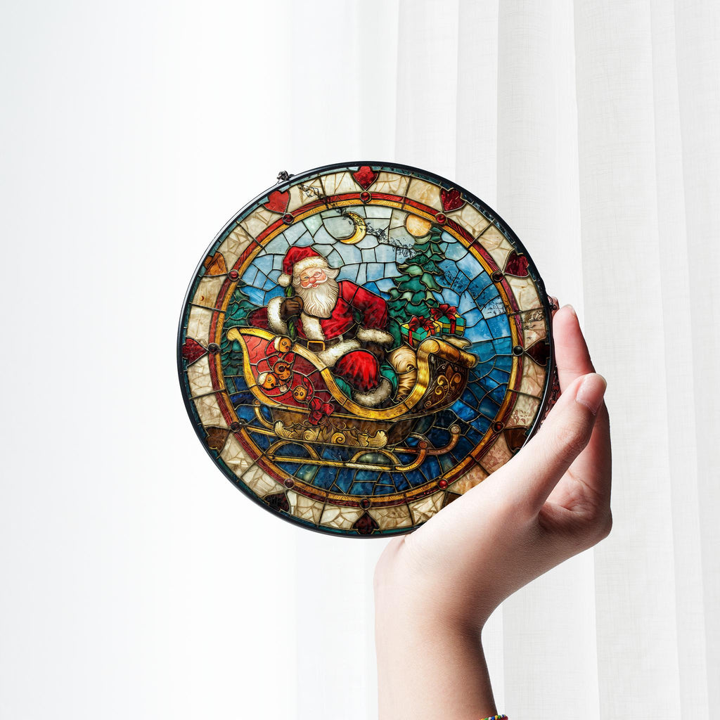 May include: A round stained glass ornament featuring a colorful depiction of Santa Claus riding in a sleigh pulled by reindeer. The ornament has a black frame and a mosaic-like design.