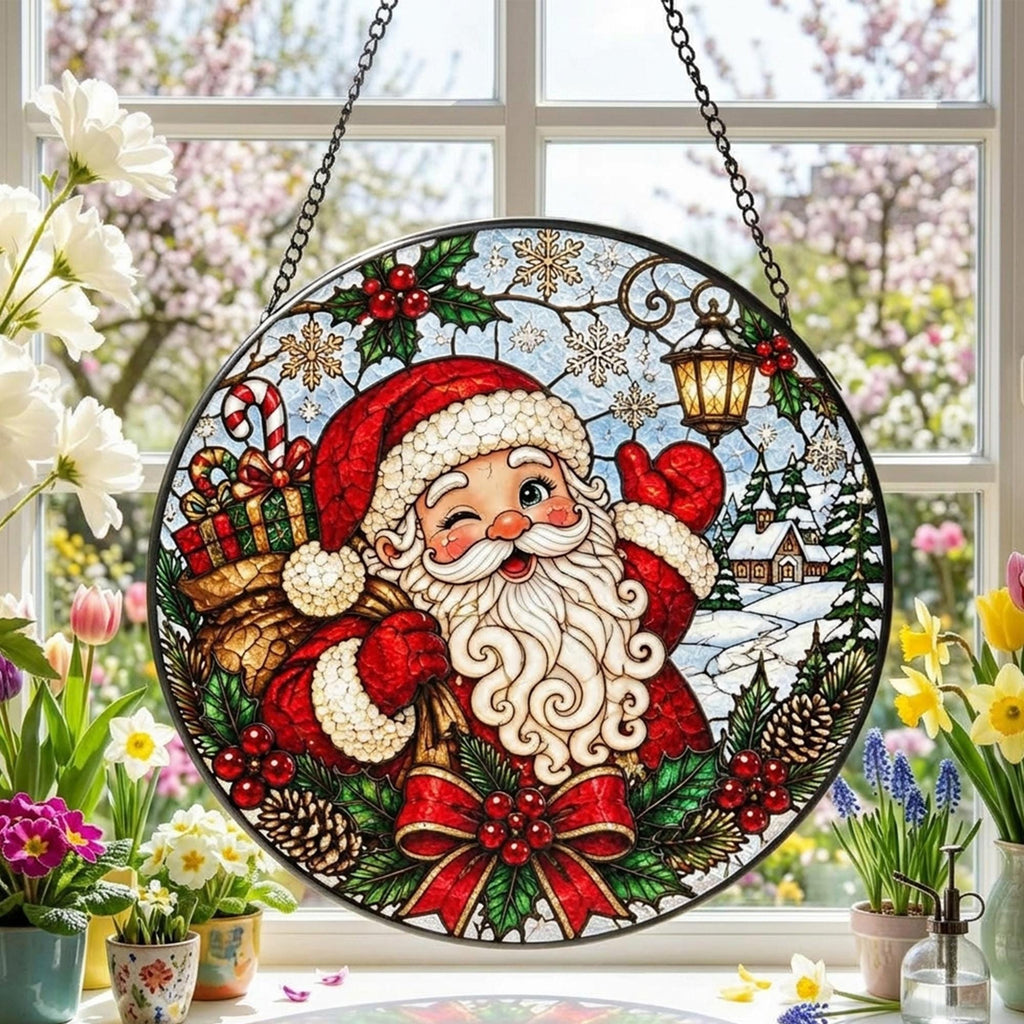 May include: A circular stained glass suncatcher featuring a winking Santa Claus with a white beard, red suit, and a sack of gifts. The design includes holly, pinecones, a lantern, and snowflakes, all framed by a black metal border with a hanging chain.