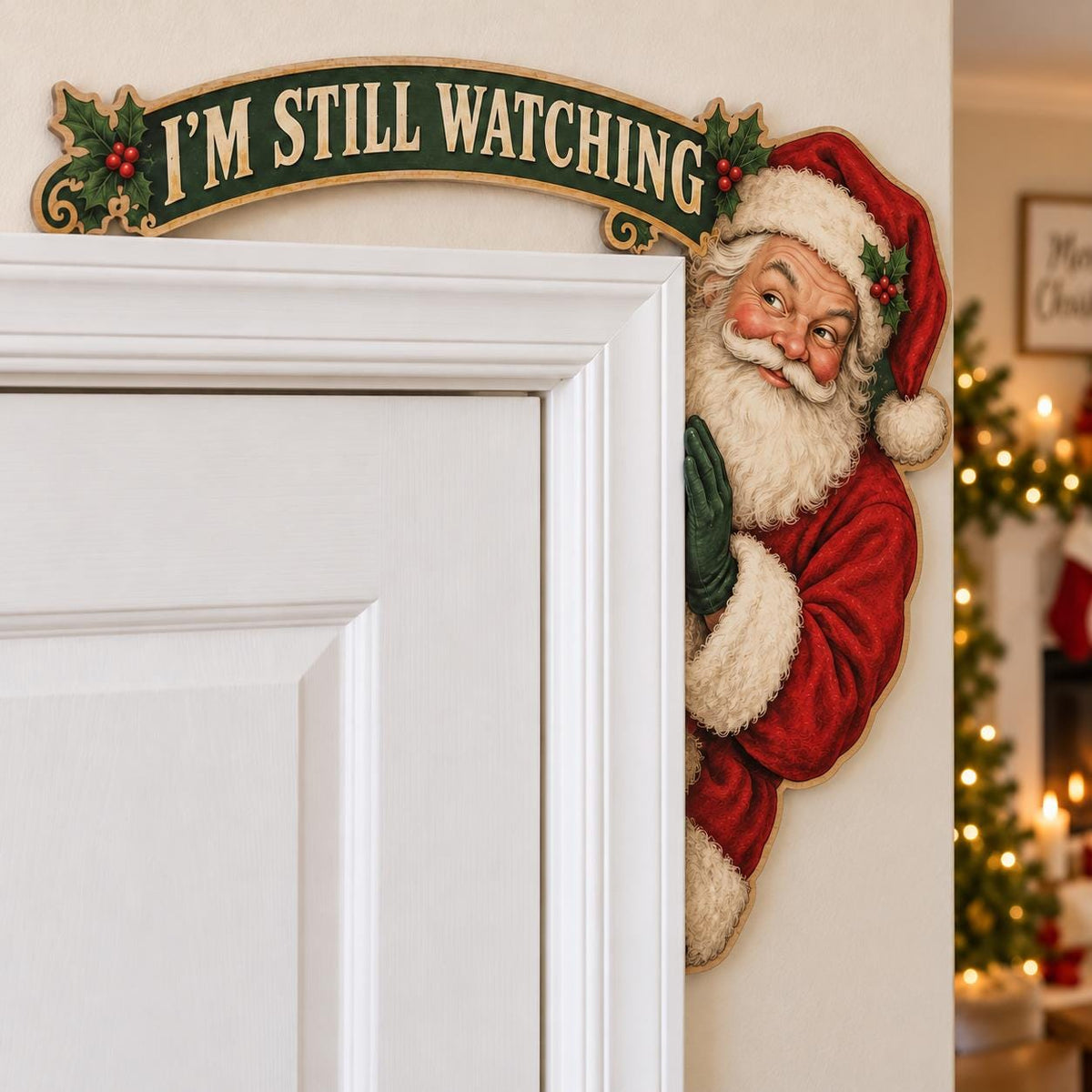 May include: A decorative door topper featuring a smiling Santa Claus in a red and white suit with a green glove, positioned next to a banner with holly accents that reads I'M STILL WATCHING in bold, cream-colored capital letters on a dark green background.
