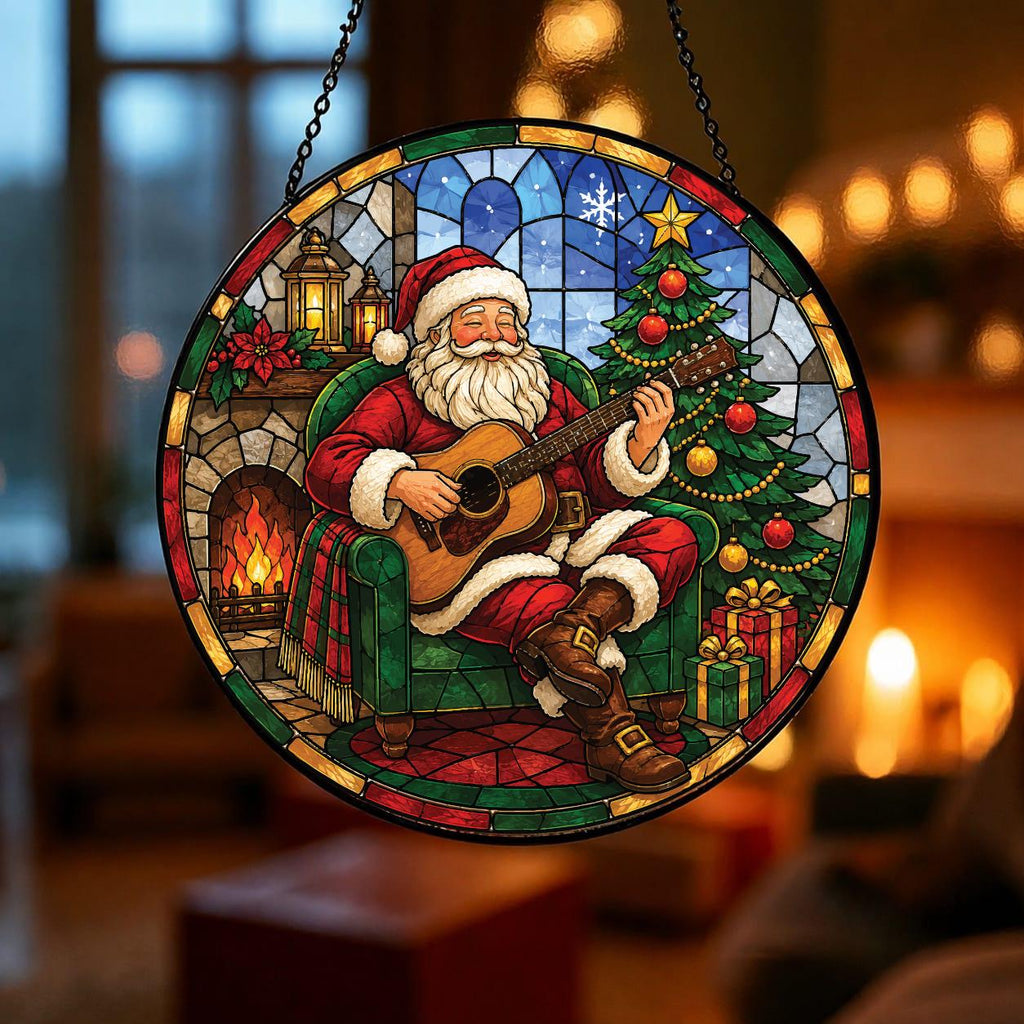 May include: A circular stained glass suncatcher featuring Santa Claus sitting in a green armchair playing an acoustic guitar. The scene includes a decorated Christmas tree, a fireplace with a lit fire, and a lantern, all rendered in vibrant colors.