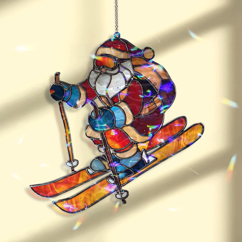 May include: Stained glass Christmas ornament depicting Santa Claus skiing downhill. The ornament features a colorful design with red, blue, orange, and white hues. Santa is wearing a red suit, a white beard, and a hat. The skis and poles are orange and yellow.