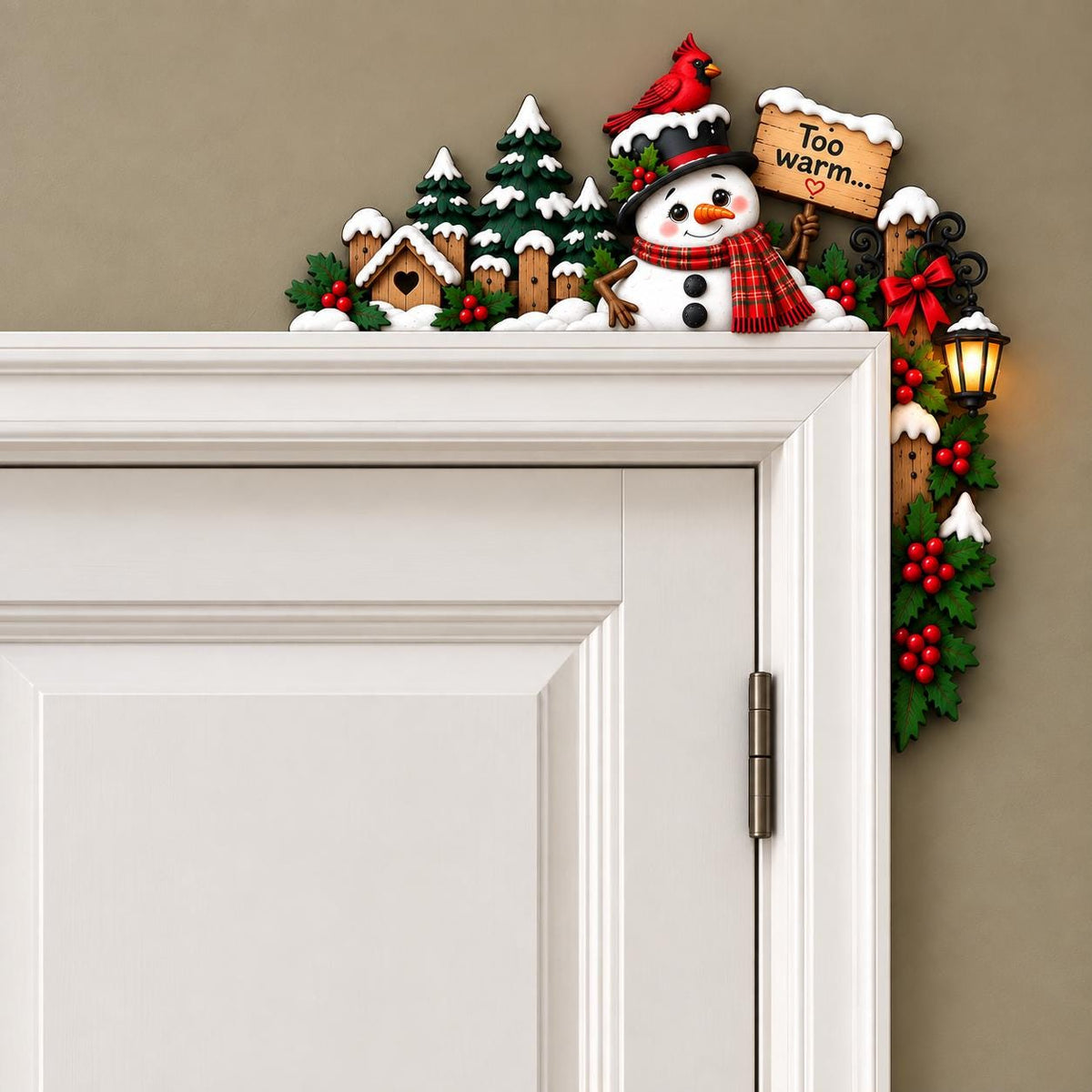 May include: A decorative door corner topper featuring a snowman wearing a red plaid scarf and top hat with a red cardinal. The scene includes snow-covered pine trees, a small house, and a wooden sign that reads Too warm... with a heart symbol.