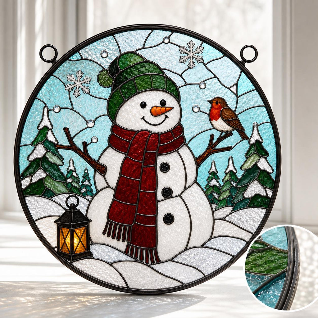 May include: A circular stained glass suncatcher featuring a white snowman wearing a green hat and a red scarf. The scene includes a small brown robin, a black lantern, and green pine trees against a light blue sky with white snowflakes.