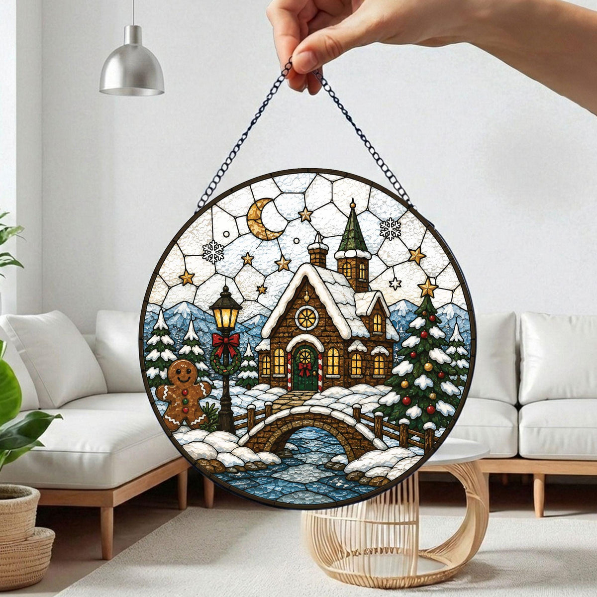 May include: A circular stained glass suncatcher featuring a winter scene with a snow-covered cottage, a stone bridge over a stream, a decorated Christmas tree, a gingerbread person, a street lamp, and a crescent moon in a starry sky.