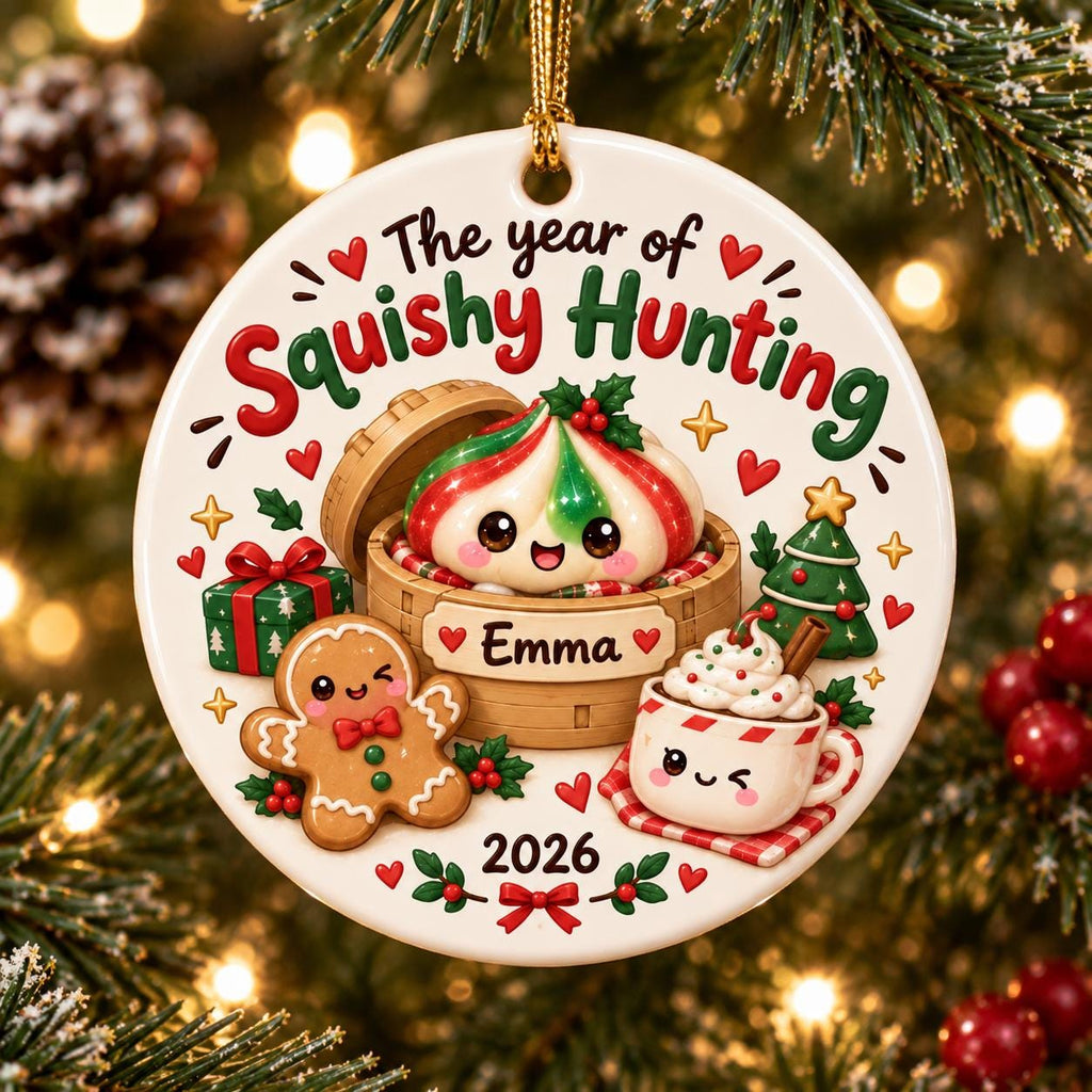 May include: A round white ceramic Christmas ornament featuring the text The year of Squishy Hunting, Emma, and 2026. The design includes a cute dumpling in a bamboo steamer, a gingerbread person, a gift box, a Christmas tree, and a mug of cocoa.