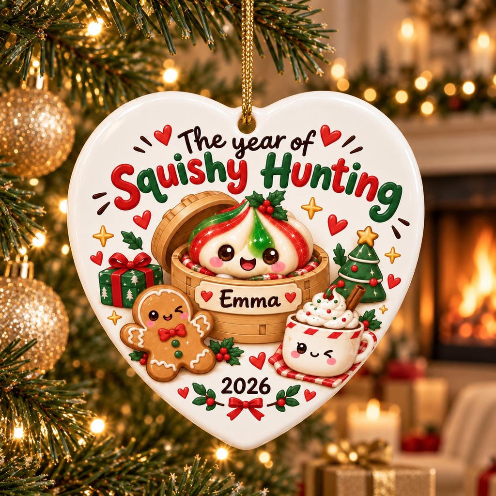 May include: A heart-shaped white ceramic ornament featuring the text "The year of Squishy Hunting" and "Emma" with "2026". The design includes a cartoon dumpling in a bamboo steamer, a gingerbread person, a gift box, a Christmas tree, and a cocoa mug.