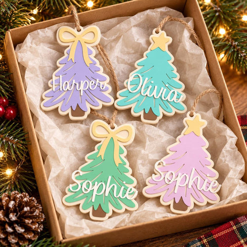 May include: Four wooden Christmas tree ornaments in a box, each with a jute twine hanger. Two are lavender with yellow bows, one is teal with a yellow star, and one is green with a yellow bow. Names Harper, Olivia, and Sophie are in white script.