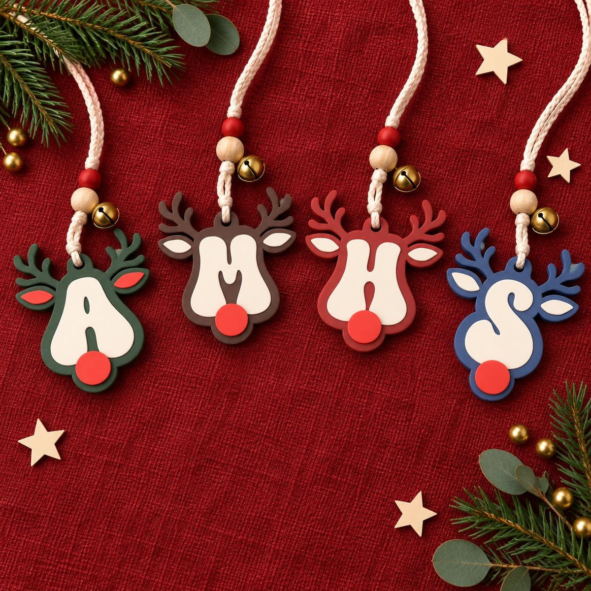 May include: Four reindeer-shaped ornaments featuring the letters A, M, H, and S in white. Each ornament has a red nose, antlers, and a braided cord with red and natural wooden beads and a small gold bell. The reindeer are dark green, brown, red, and blue.