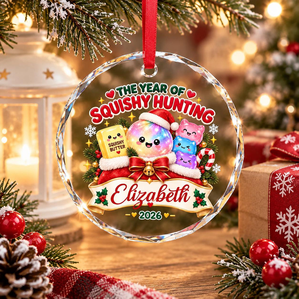 May include: A round, clear acrylic Christmas ornament featuring a colorful graphic of a smiling, iridescent sphere wearing a Santa hat, surrounded by small squishy toys, a butter block labeled Squishy Butter, and the text The Year of Squishy Hunting.