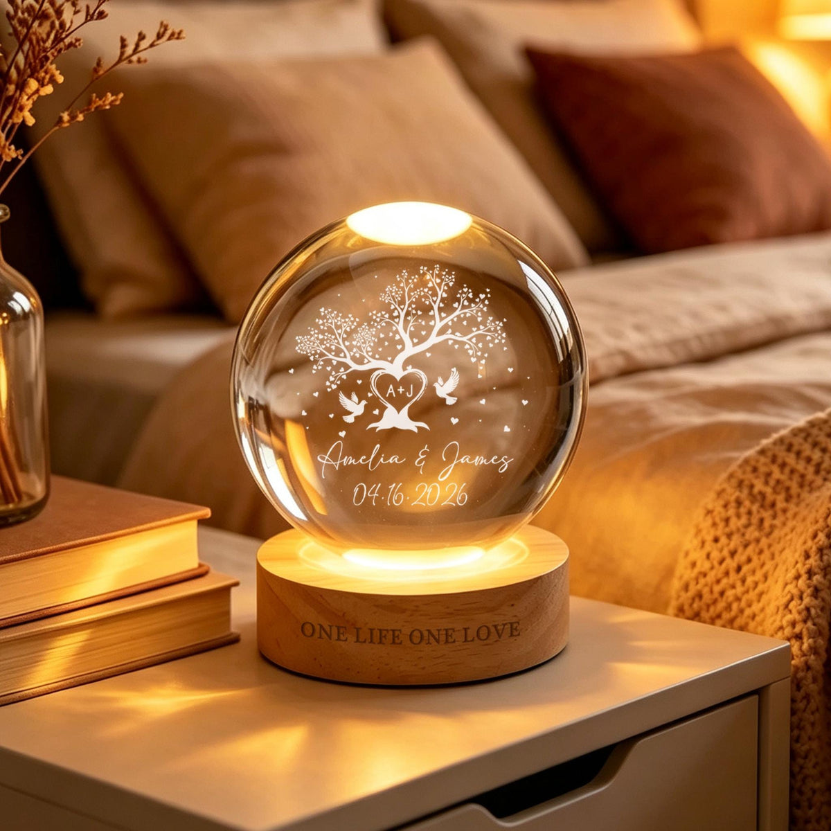 May include: A spherical glass lamp on a round wooden base. The glass features an etched tree, two birds, a heart with the initials A+J, the names Amelia & James, and the date 04.16.2026. The wooden base is engraved with the text ONE LIFE ONE LOVE.