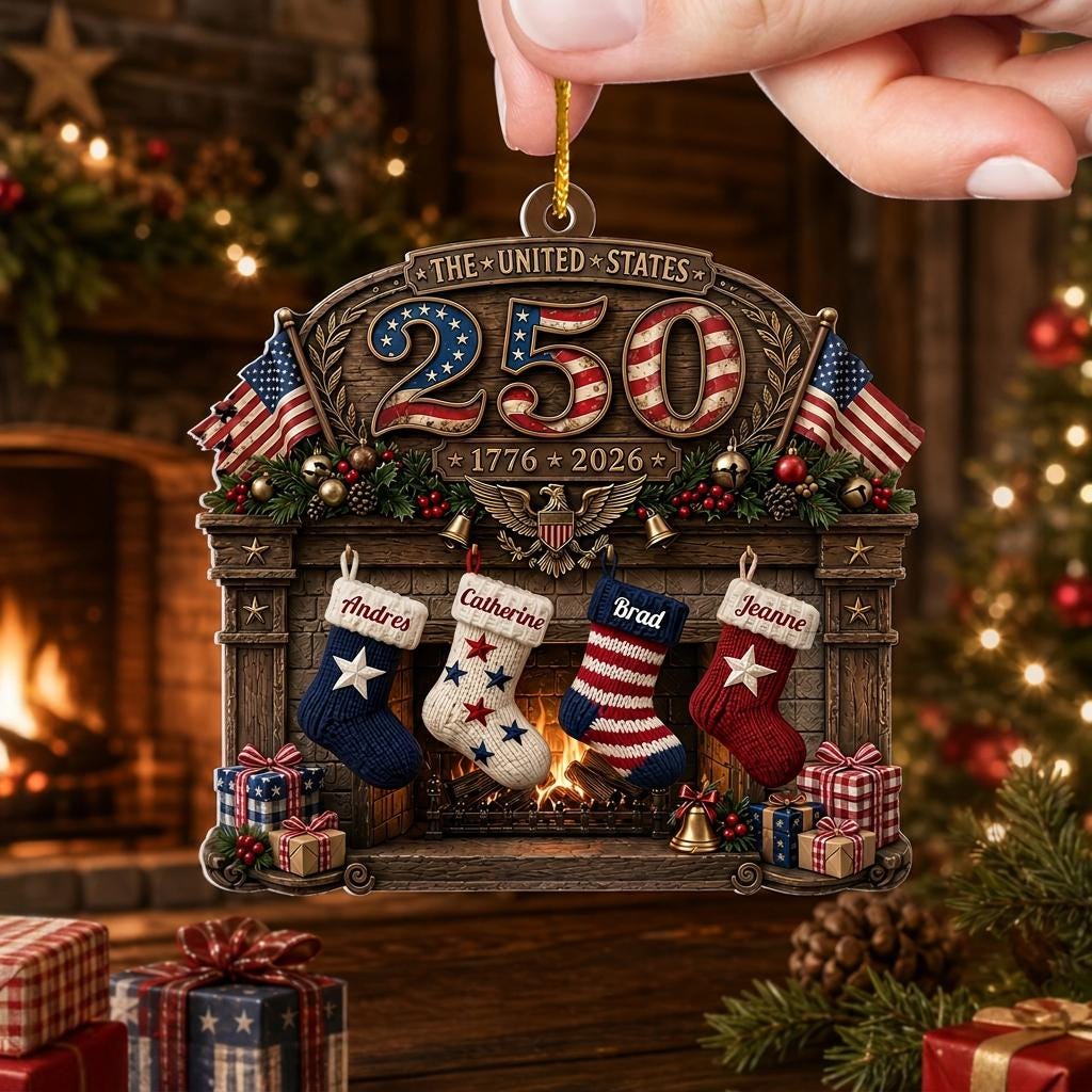 May include: A decorative Christmas ornament featuring a fireplace scene with the text THE UNITED STATES 250 and 1776 2026. It displays four hanging stockings labeled Andres, Catherine, Brad, and Jeanne, two American flags, and wrapped gift boxes.