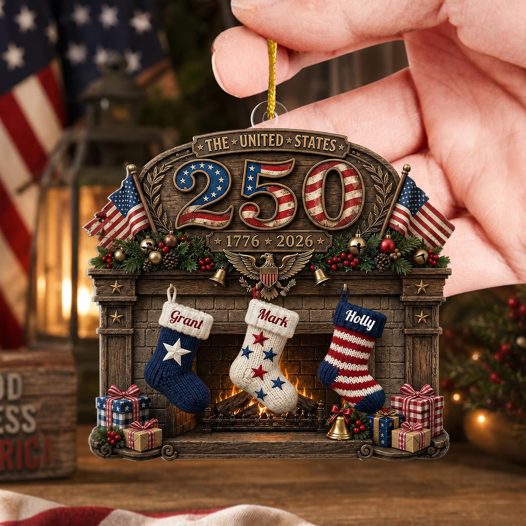 May include: A decorative ornament featuring a fireplace scene with the text THE UNITED STATES 250 and 1776 2026. Three stockings labeled Grant, Mark, and Holly hang from the mantel, flanked by American flags, wrapped gifts, and a central eagle emblem.