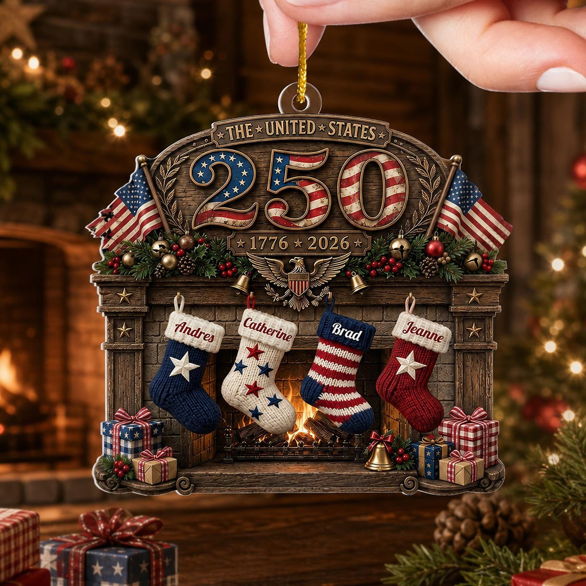 May include: A decorative hanging ornament featuring a fireplace scene with the text THE UNITED STATES 250 and 1776 2026. It includes four stockings labeled Andres, Catherine, Brad, and Jeanne, two American flags, and a central eagle emblem.